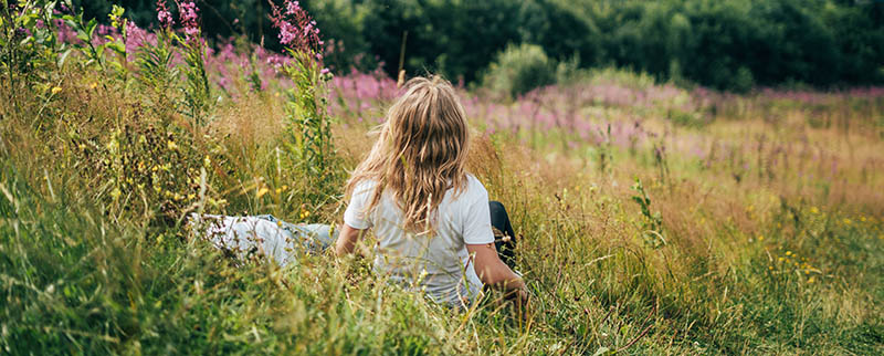 A Girl In A White T-shirt And Blond Hair Sits On A Slope And Enj